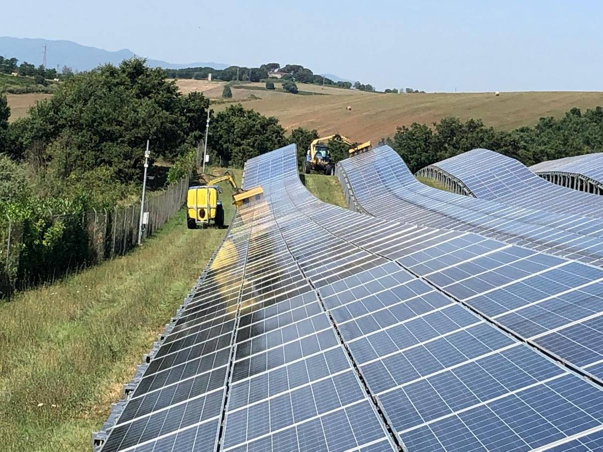 Sfalcio dell'erba tra le file di pannelli di un parco fotovoltaico